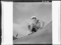 Naval air base, Corpus Christi, Texas. M.M. Bremer, A.M.M, 2nd Class, keeps planes in first class condition at the naval air base in Corpus Christi, Texas. Every plane in use at the base is subjected to frequent and minute inspections by sailors such as this one. Sourced from the Library of Congress.