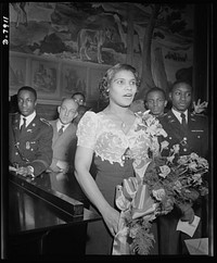 Marian Anderson mural dedicated. Marian Anderson, noted contralto, sings "The Star Spangled Banner" at the dedication of a mural commemorating her free public concert on the steps of the Lincoln Memorial on Easter Sunday, 1939. The dedication was held in the Department of Interior Auditorium before a distinguished audience on January 6, 1943. Miss Anderson is holding a bouquet of roses presented to her by African American high school cadets who served as ushers at the ceremony. Secretary of Interior Ickes accepted the mural for the government. Sourced from the Library of Congress.