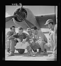 U.S. desert airmen check bombing plans. The crew of an U.S. Army Air Force B-25 bomber check their flight plans at a desert air base before taking off to bomb advance Axis position. They are (left to right) Lieutenant Bob Hill, Clear Lake, Iowa, bombardier; Lieutenant Bill Brytan, Denton, Texas, pilot; Lieutenant Jack Cross, Austin, Texas, navigator (he's checking the time); and Lieutenant Don Castle, Saint Joseph, Missouri, co-pilot; (crew member in rear is unidentified). Sourced from the Library of Congress.