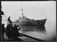 Big U.S. naval base in Ulster built by American and British workers. Londonderry is now America's premier naval base in Europe. Nearly 800 American technicians, with over 2,000 local workers, built it in six months, all the equipment down, to the last nut and bolt, coming from the U.S.A. American and British sailors warmly fraternized during the building of the base, which includes receiving and broadcasting stations, a 200-bed hospital, and large camps. Pictures taken when the first American warships escorting a convoy across the Atlantic arrived at Londonberry in January. The white ensign and the Old Glory fly side by side. The photograph was taken at the base, where British and American warships lie along side each other. Sourced from the Library of Congress.