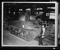 Production. M-4 tanks. Cannon and front turret armored plate are lowered into place on an M-4 tank. Machine guns have already been installed and the General Sherman will be ready for the test track. Designed by the Army Ordnance Department and built under ordnance supervision, the M-4 embodies new advances in design based on battlefront experience. Cast steel construction of the hull expedites production. Sourced from the Library of Congress.