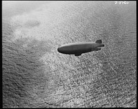 U.S. Navy starts out on patrol duty. Soaring over the Atlantic Ocean, a U.S. Navy blimp is silhouetted against the sparkle of waves. These lighter-than-air craft are used for anti-submarine patrols. Sourced from the Library of Congress.