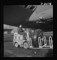 Production. B-17 heavy bomber. A landing wheel, with its huge rubber "shoe," is trundled out in a service tractor to a new B-17F (Flying Fortress) bomber awaiting completion at Boeing's Seattle plant. The tractor operator, like half of the plant's workers, is a woman. The Flying Fortress has performed with great credit in the South Pacific, over Germany and elsewhere. It is a four-engine heavy bomber capable of flying at high altitudes. Sourced from the Library of Congress.
