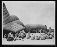 Balloon barrage training center. Lilluputians at a weemie roast. This illustration is portrayed here by comparing the huge balloons and dwarfed trainees seated in picnic fashion around their instructor. Camp Tyson, Tennessee. Sourced from the Library of Congress.