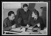 Reciprocal aid. Close cooperation exists between members of the British and U.S. air forces in Britain. Two U.S. sergeants are here shown at work in a coding room with a British WAAF (Women's Auxiliary Air Force) section officer. Sourced from the Library of Congress.