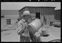 Pouring gasoline into tractor, large farm near Ralls, Texas. Man is day laborer by Russell Lee
