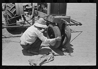 Day laborer testing play on front wheel bearing of tractor, farm near Ralls, Texas by Russell Lee