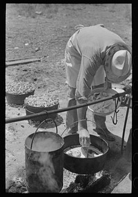 Camp cook working over an open fire, cattle ranch near Spur, Texas. The old attitude of the inferiority of the cook on the range is still prevalent. This cook said "the boys treat me awfully good." by Russell Lee