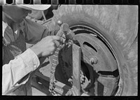 Day laborer repairing link of chain which operates planter feed, farm near Ralls, Texas by Russell Lee