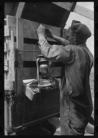 Tying the lantern onto the back of improvised truck which will travel to California near Muskogee, Oklahoma by Russell Lee