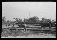 [Untitled photo, possibly related to: Unloading pipe from truck at oil well, Seminole oil field, Oklahoma] by Russell Lee