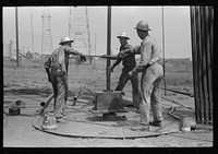 [Untitled photo, possibly related to: Roughnecks leaning on the wrench to tighten the joint in the pipe, oil well, Oklahoma City, Oklahoma] by Russell Lee