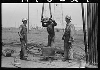 [Untitled photo, possibly related to: Roughnecks leaning on the wrench to tighten the joint in the pipe, oil well, Oklahoma City, Oklahoma] by Russell Lee