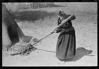 Pulling out hot coals with wet cloth, Taos County, New Mexico by Russell Lee