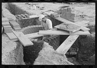 [Untitled photo, possibly related to: Laying bricks in construction of manhole at migrant camp at Sinton, Texas] by Russell Lee