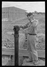 Working on sewer pipe connection at migrant camp under construction at Sinton, Texas by Russell Lee