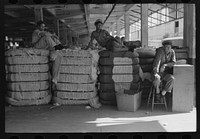[Untitled photo, possibly related to: Loading bale of cotton onto hand truck at platform. Cotton compress, Houston, Texas] by Russell Lee