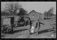 Son of Pomp Hall,  tenant farmer, carrying can full of mash to hogpen, Creek County, Oklahoma. See general caption, number 23 by Russell Lee