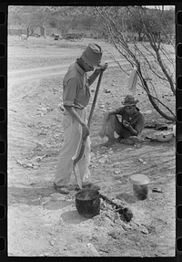 Professional goat and sheep shearer moving kettle closer to the coals while he cooks the noonday mean on the ranch of a rehabilitation borrower in Kimble County, Texas by Russell Lee