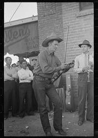 Member of orchestra which plays outside grocery store on Saturday afternoon tuning his violin, Phoenix, Arizona by Russell Lee