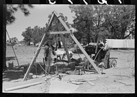 [Untitled photo, possibly related to: Woman guiding the drilling tool for water well drilling. Pie Town, New Mexico] by Russell Lee