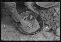 Pan of slush taken from "rocker." This pan will be rotated slowly with the hands, the waste thrown away as the gold sinks to the bottom until only the fine dirt and gold and little water remain. Pinos Altos, New Mexico by Russell Lee