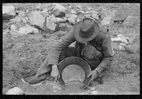 Prospector washing a "pan" of gold-bearing dirt. Pinos Altos, New Mexico by Russell Lee