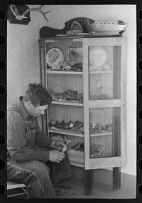 [Untitled photo, possibly related to: George Hutton, Jr. examines fetish used in Indian cermonies. He has a collection of rocks, curios, and Indian relics which is highly prized by the entire family. Pie Town, New Mexico] by Russell Lee