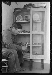 George Hutton, Jr. examines fetish used in Indian cermonies. He has a collection of rocks, curios, and Indian relics which is highly prized by the entire family. Pie Town, New Mexico by Russell Lee