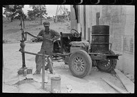 [Untitled photo, possibly related to: Homesteader pumping water which he will haul home from town. Wells require cash to drill and some farmers have not yet been able to drill their own wells. Pie Town, New Mexico] by Russell Lee