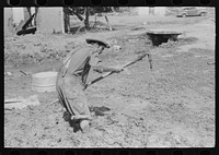 Spanish-American mixing adobe plaster, Chamisal, New Mexico by Russell Lee