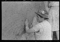 After plaster is applied with towel it is smoothed out with the hands. The women pride themselves on careful plastering, Chamisal, New Mexico by Russell Lee