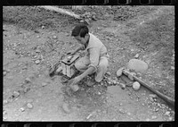 [Untitled photo, possibly related to: A Spanish-American boy dipping water from irrigating ditch. Water will be used in house for cooking, drinking, etc. Chamisal, New Mexico] by Russell Lee