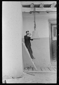 Spanish-American ringing bell with rock at the Church of the Twelve Apostles, Trampas, New Mexico. Church is 350 years old by Russell Lee