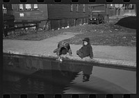 Children playing in water backed up in gutter, South Side of Chicago, Illinois by Russell Lee