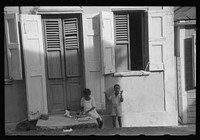 [Untitled photo, possibly related to: Little girl playing with her Christmas presents on a side street in Charlotte Amalie, Virgin Islands]. Sourced from the Library of Congress.