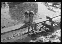 Children sitting on one of the boardwalks which are as sidewalks in the slum area known as "El Fangitto" (The Mud) in San Juan, Puerto Rico. Sourced from the Library of Congress.