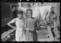 Two of the residents of houses on the outskirts of the slum area known as "El Fangitto" (The Mud) in San Juan, Puerto Rico. Sourced from the Library of Congress.