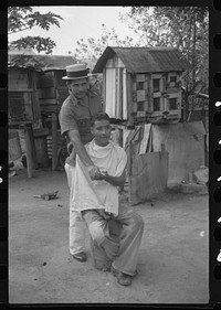 [Untitled photo, possibly related to: Yabucoa, Puerto Rico. Striker getting a haircut in the mill village near the sugar mill]. Sourced from the Library of Congress.