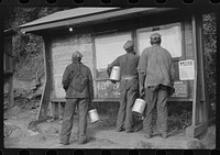 Miners looking at daily reports, checking the number of tons of slate and coal they loaded during their shift. Also to find out whether or not they work the next day. Caples, West Virginia. Sourced from the Library of Congress.
