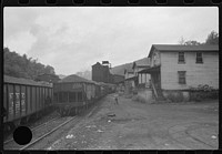 [Untitled photo, possibly related to: Coal miner's child taking home kerosene for lamps. Company houses, coal tipple in background. Pursglove, Scotts Run, West Virginia]. Sourced from the Library of Congress.