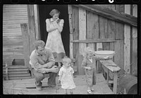 [Untitled photo, possibly related to: Coal miner and two of his children on their back porch. Bertha Hill, West Virginia]. Sourced from the Library of Congress.
