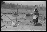 Charles McGuire's wife and baby looking at their new poultry yard and pen with biddies. Tenant purchase clients. Pike County, Alabama. Sourced from the Library of Congress.