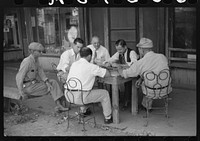 Playing dominoes or cards in front of drug store in center of town, in Mississippi Delta, Mississippi. Sourced from the Library of Congress.