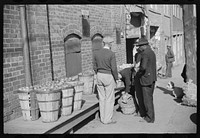 [Untitled photo, possibly related to: Farmer having corn removed from his foot on street outside tobacco warehouse during auction sales, Durham, North Carolina]. Sourced from the Library of Congress.