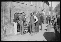 [Untitled photo, possibly related to: Farmer having corn removed from his foot on street outside tobacco warehouse during auction sales, Durham, North Carolina]. Sourced from the Library of Congress.