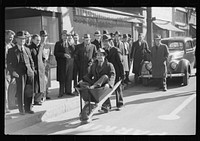 Tobacco auctioneer who "bet on Carolina" and lost, pays off the wager by pushing the warehouseman in a wheelbarrow from the warehouse to the courthouse. Durham, North Carolina. Sourced from the Library of Congress.