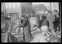 [Untitled photo, possibly related to: Farmers and warehousemen unloading tobacco on sidewalk, before auction sale. The warehouse was too overloaded to permit more tobacco being brought in. Mebane, North Carolina]. Sourced from the Library of Congress.