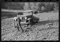 Mountaineer trying to change tire with a fence post as a jack. Up South fork of the Kentucky River. Breathitt County, Kentucky. Sourced from the Library of Congress.