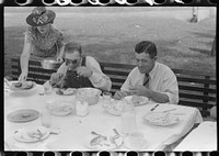 Eating dinner served for benefit of the church in courthouse yard on court day. Campton, Wolfe County, Kentucky. Sourced from the Library of Congress.